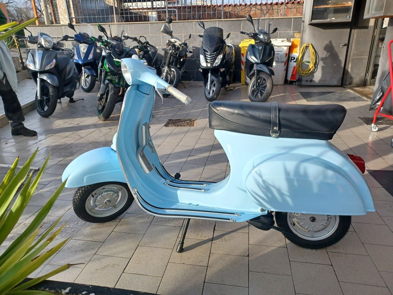 Scooter d'epoca azzurro restaurato, parcheggiato davanti all'officina